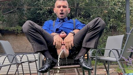 رجل يرتدي بدلة ويحمل قضيبًا مقفلًا يعبث بفتحة شرجه ويتبول في الأماكن العامة وهو يرتدي جوارب شفافة
